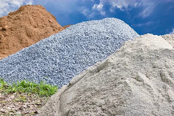 A heap of crushed stone alongside a heap of sand