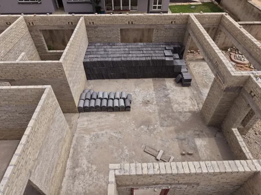 Aerial view of grey block walls forming rooms, with lintels stacked ready on the floor