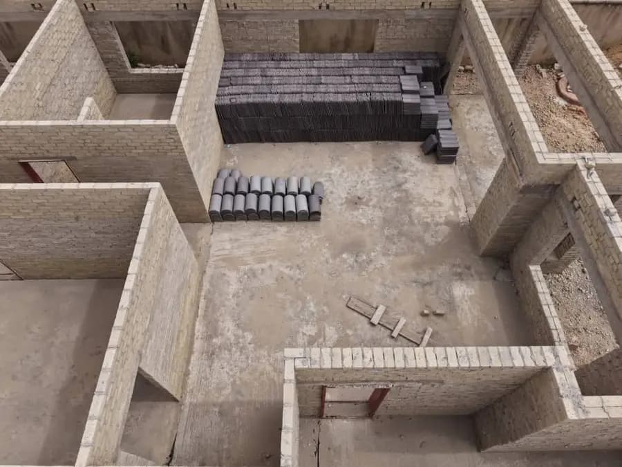 Aerial view inside the block walls of a building under construction, with precast lintels stacked on the floor