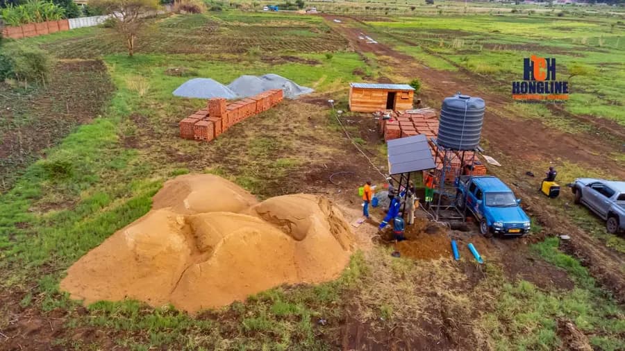 Aerial view of a borehole drilling site with the rig set up, blue pipe laid out and crew working around it