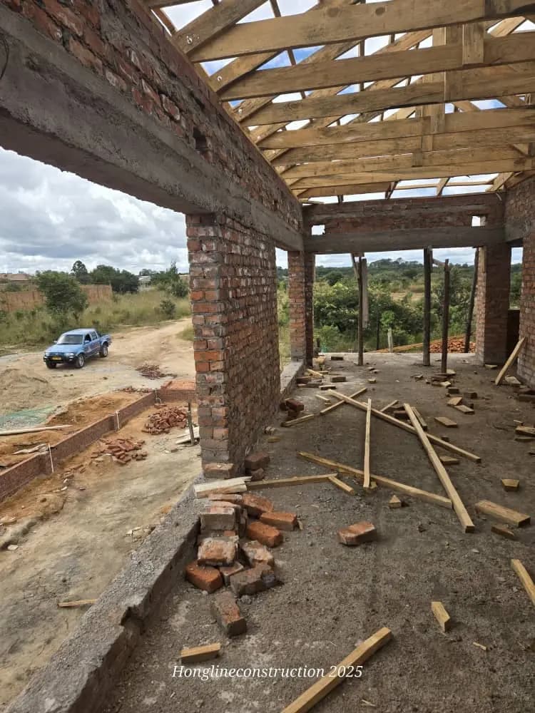 The inside of a building under construction, brick columns carrying a timber roof structure overhead