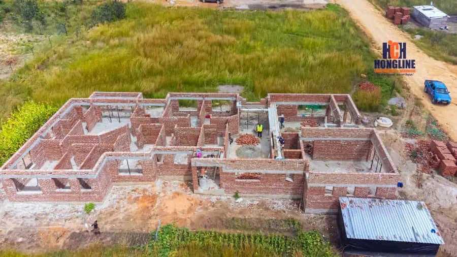 Aerial view of the brick walls of a house under construction on open green farmland
