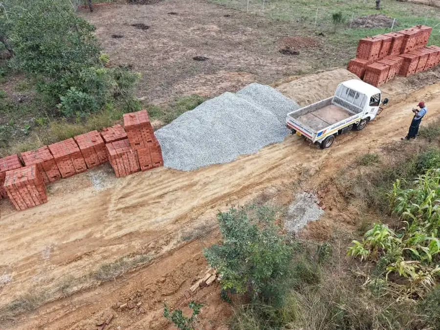 Aerial view of a truck and stacks of brick on a plot cleared out of thick bush