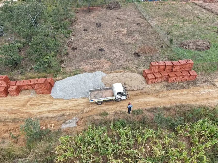 Aerial view of a cleared plot with brick stacks, a sand heap and a small tipper truck