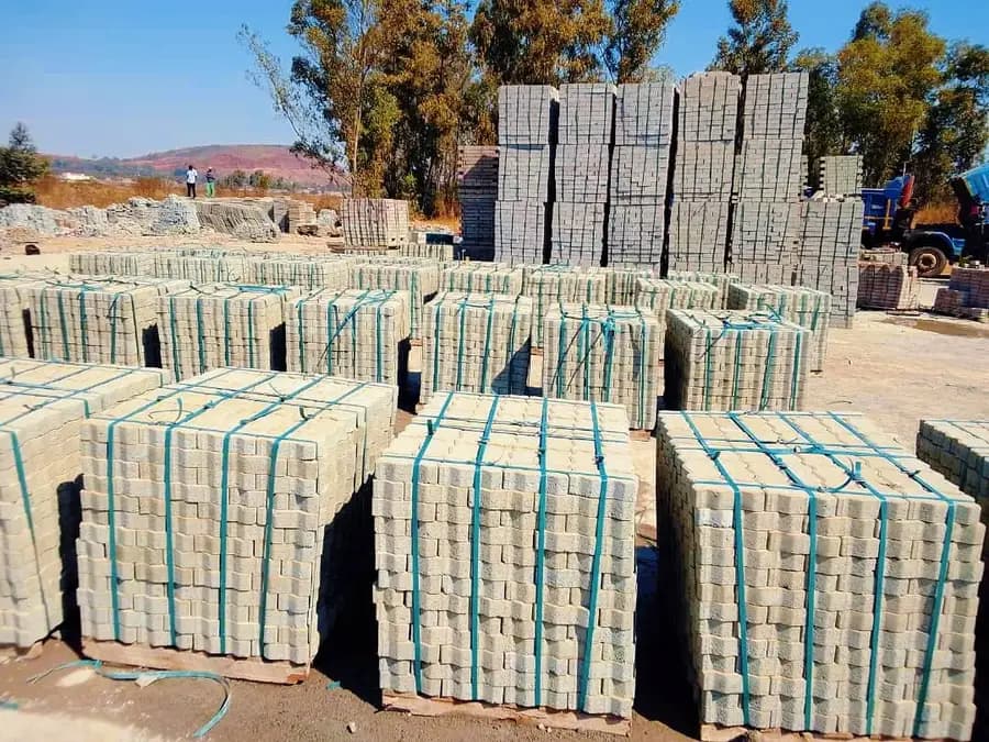 Pallets of grey concrete blocks strapped and stacked in rows at a yard