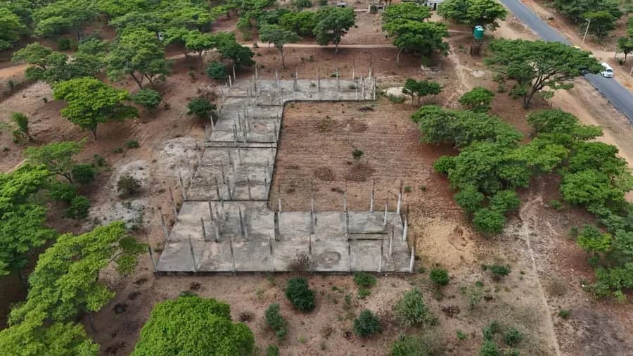 Aerial view of concrete footings laid out in trenches across a cleared plot surrounded by bush