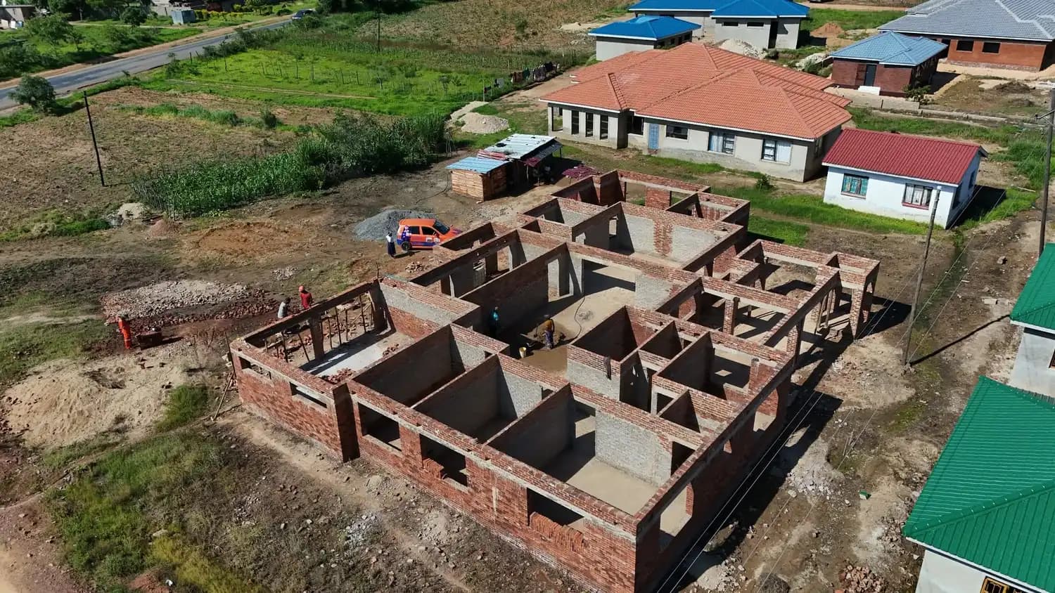 Aerial view of a brick house under construction next to a completed house