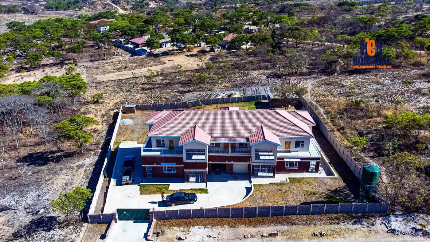 Aerial view of a completed house with a red tiled roof, paved driveway and finished yard
