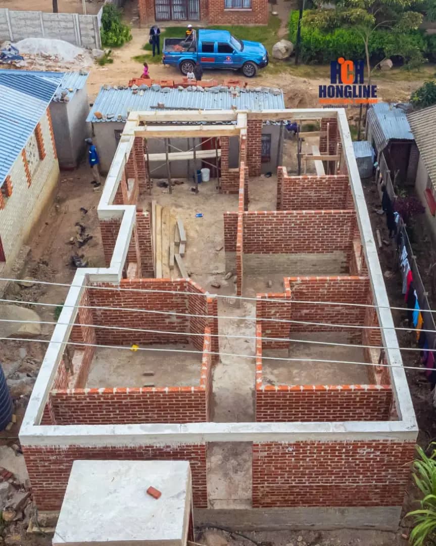 Aerial view of brick walls at floor level across a house footprint, with a Hongline banner hung on the boundary wall