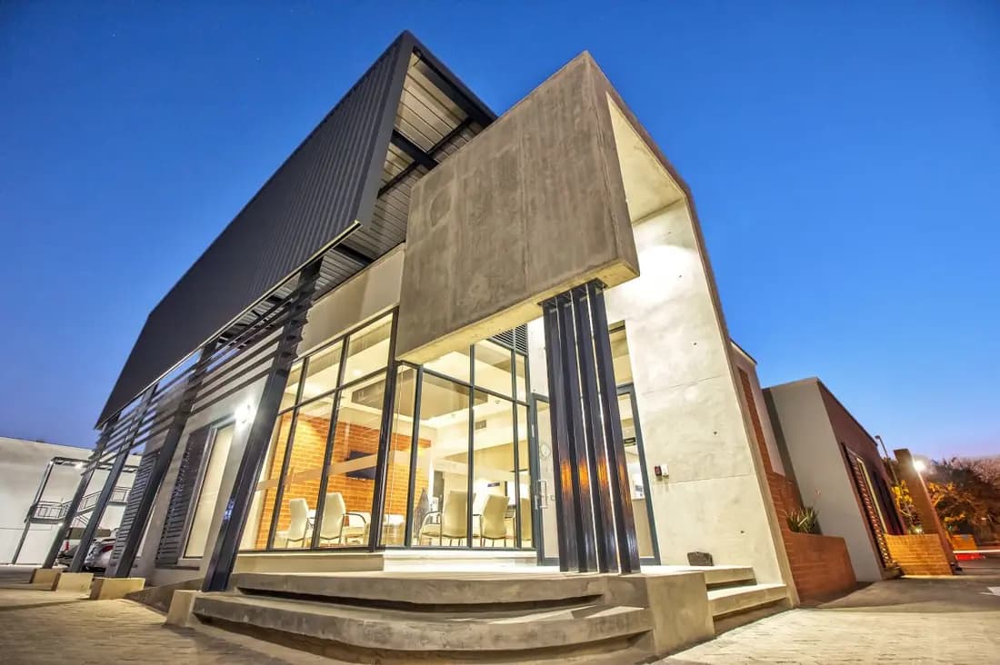A contemporary house at dusk, lit from inside through full-height glazed doors