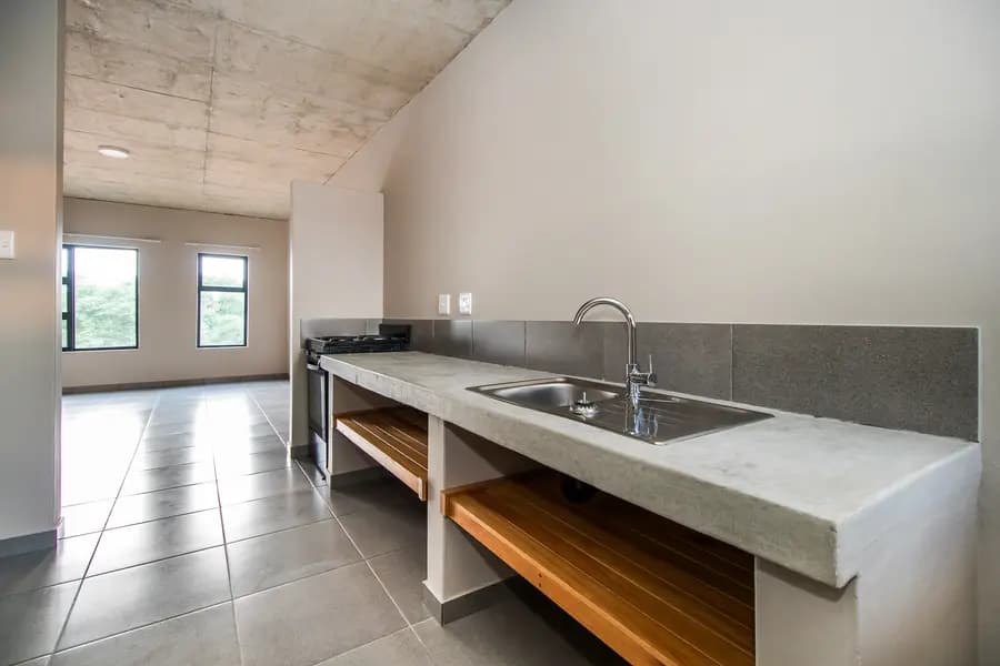A plain kitchen with a cast concrete worktop, undermount sink and tiled floor