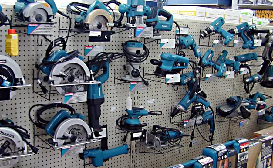 Power tools — grinders, circular saws and sanders — hung on a shop display board