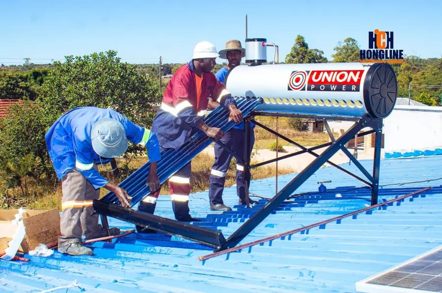 Three workers in hard hats lifting a solar geyser cylinder onto its roof frame