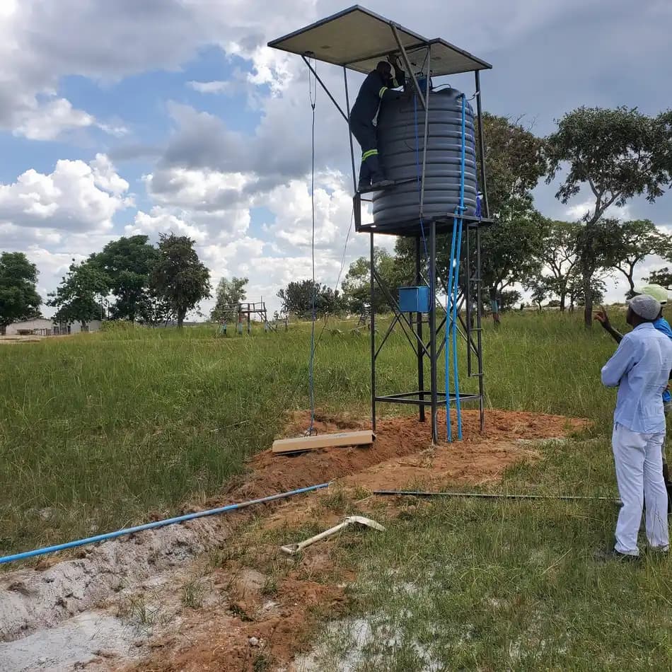 A water tank on a steel stand with a solar panel, plumbed in on open ground